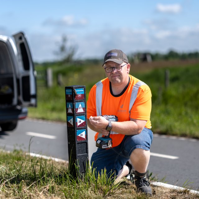Anton ten Have die onderhoud doet aan een van de paaltjes met wandelroutes