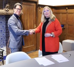 Bestuurder Joeri Kapteijns van het COA (links) en burgemeester Van Toorenburg (rechts) schudden elkaar de hand na het ondertekenen van de bestuursovereenkomst