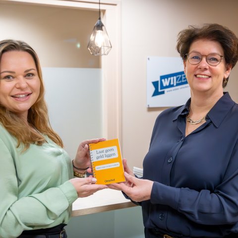 Wethouder Corine van Overdijk overhandigt het eerste exemplaar aan Anique Smulders van het Sociaal Raadsliedenwerk.
