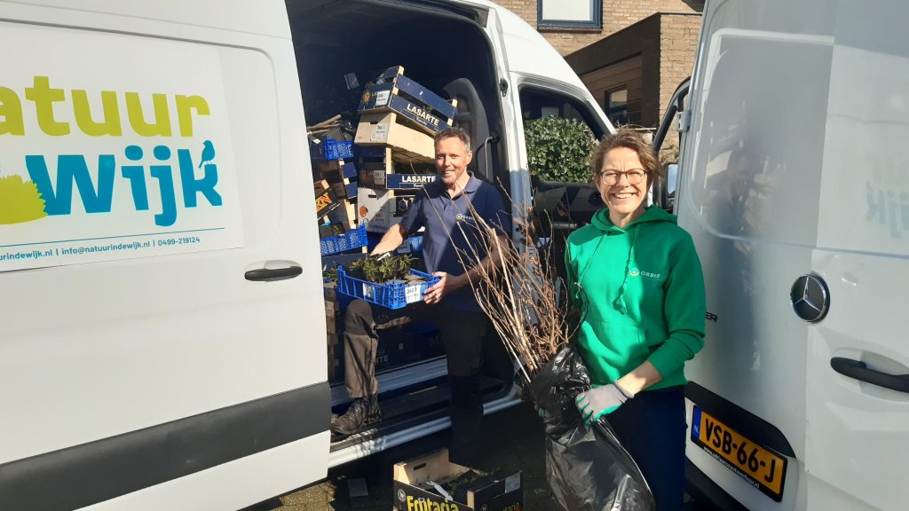 2 mensen met planten in de hand bij een bus van Natuur in de wijk