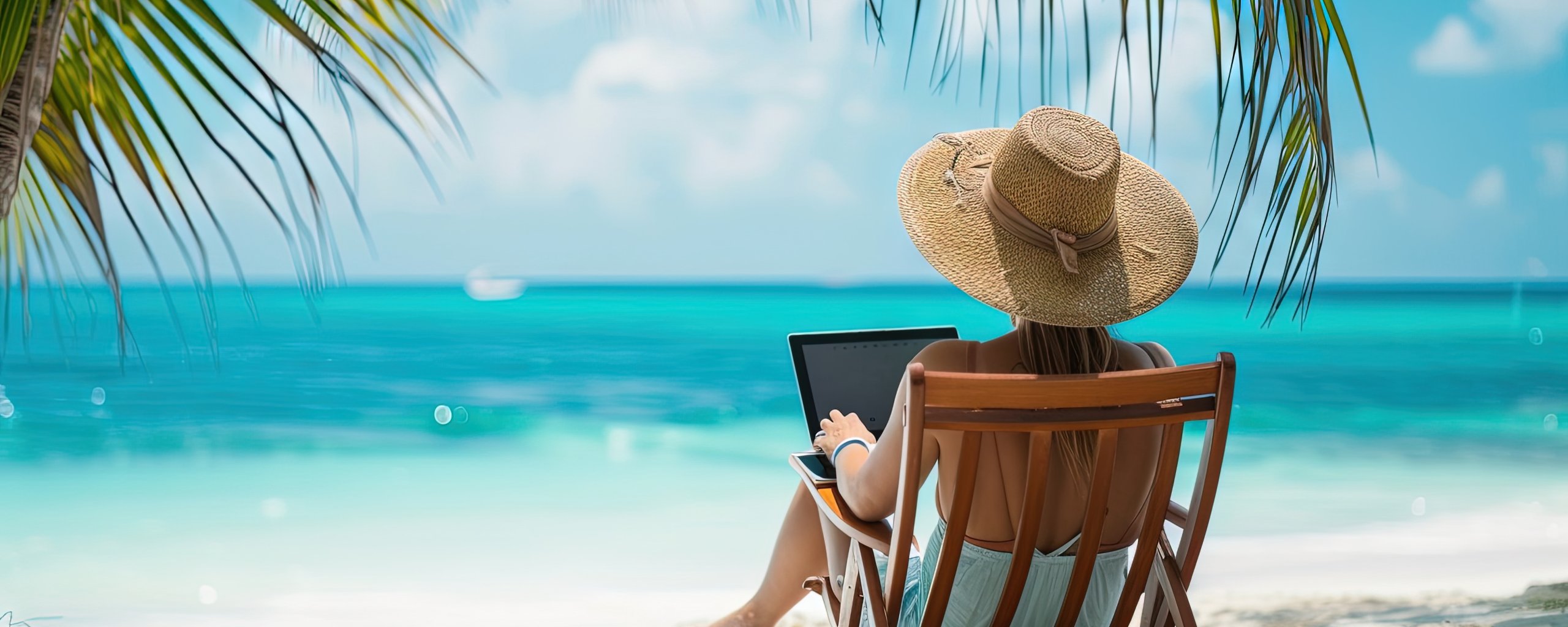 Vrouw op strandstoel aan strand met laptop op schoot