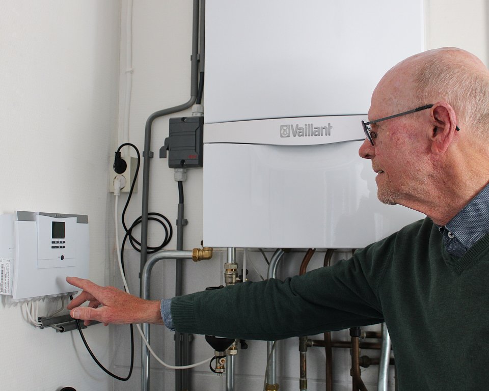 Jelle Popkema wijst het bedieningspaneel van de hybride warmtepomp aan