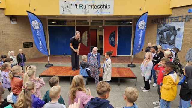 Afbeelding van twee basisschoolkinderen die samen met de burgemeester de plaquette Gezonde School onthullen.