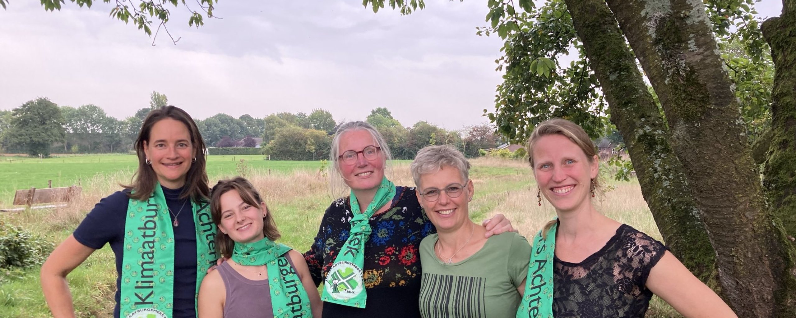 Vijf klimaatburgmeesters onder een boom met groene sjaal om