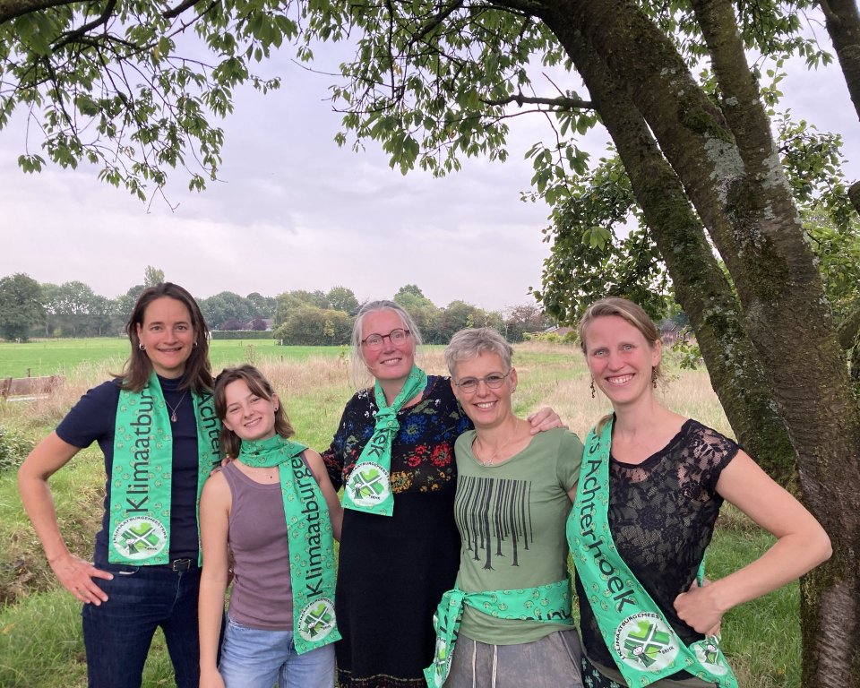 Vijf klimaatburgmeesters onder een boom met groene sjaal om