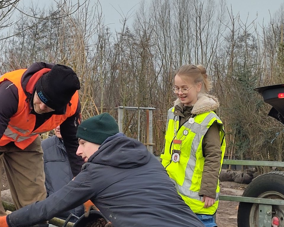 Lara de jeudburgemeester staat met een geel hesje aan in de aanhangwagen om te helpen een boom in te laden