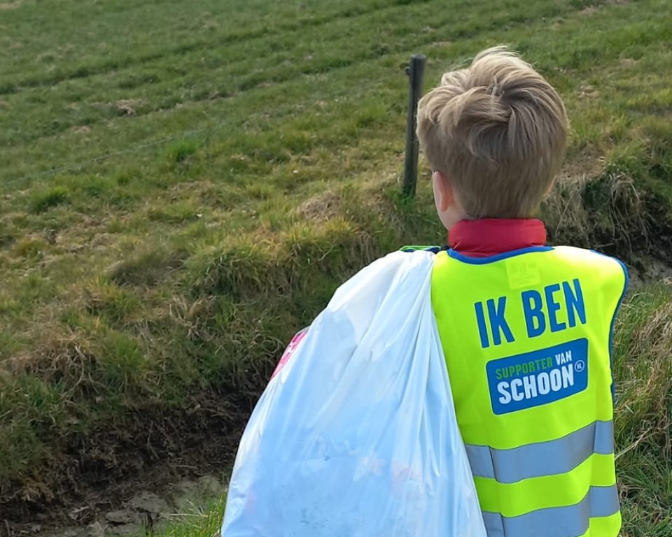 Kind met vuilniszak raapt rommel op
