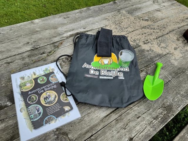 Rugzakje ligt met schepje, boekje en insectenpotje op picknicktafel