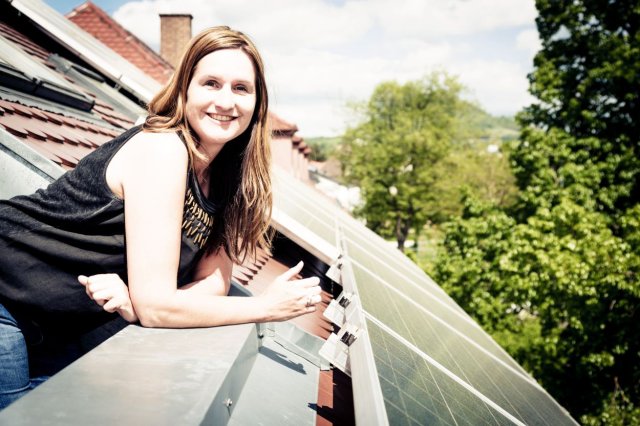 Vrouw kijkt uit dakraam over een dak met zonnepanelen