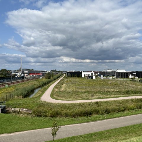 Bedrijventerrein De Aam in Elst met grasveld, spoorlijn en bedrijfsgebouwen