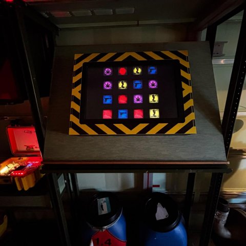 Binnenkant escaperoom digitaal scherm met iconen voor drugs, sex, geweld ook twee blauwe vaten en koffer met een soort bom
