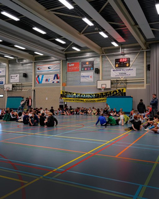 Foto in sportgal van VVV-Venlo Futsaltoernooi, alle kinderen zitten op de grond