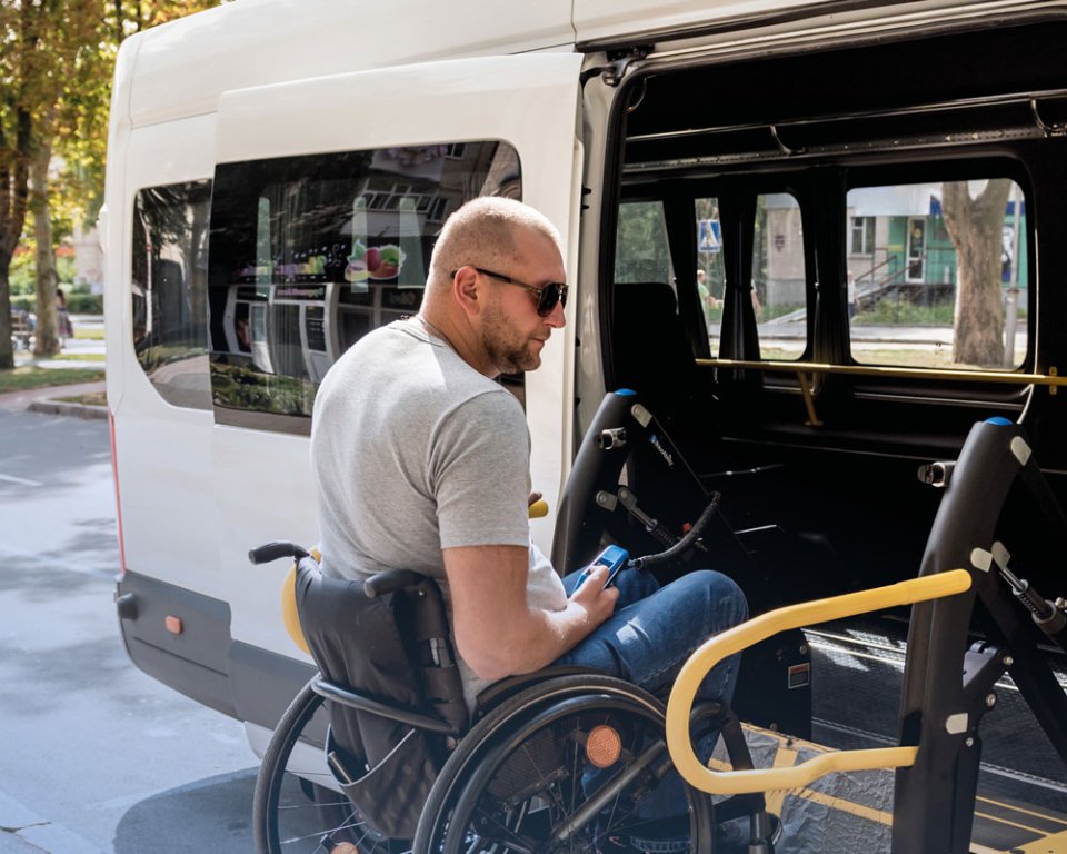 man in rolstoel wordt geplaatst in een bus