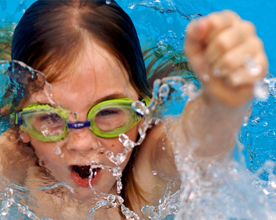 een meisje met zwembril juicht in het water