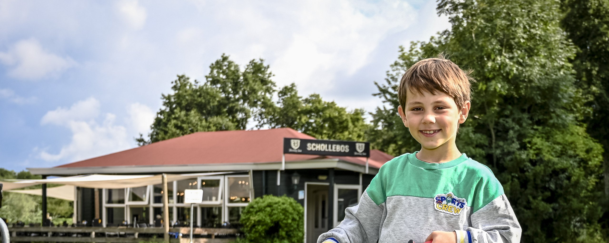 Een jongen met een emmer en een afvalgrijper voor het Pannekoekenhuis