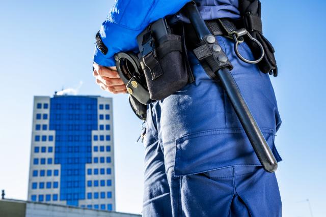 Politiagent gezien van middel naar beneden met wapenstok voor gemeentehuis Capelle