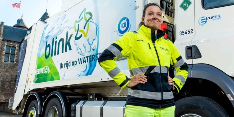 Een medewerkster van Blink poseert voor een vrachtwagen voor een bedrijf