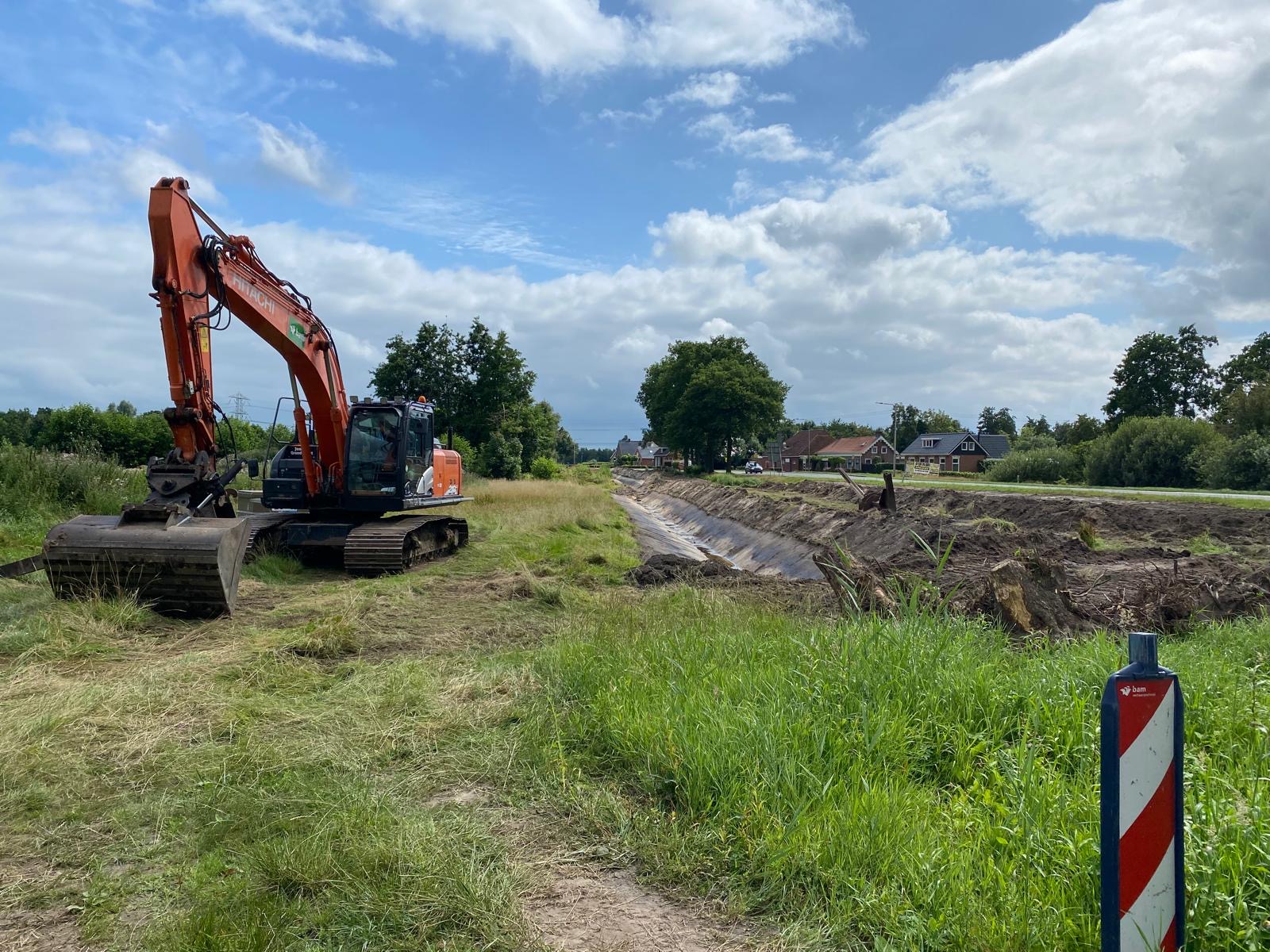 Een kraan staat in een grasveld waar gegraven wordt.