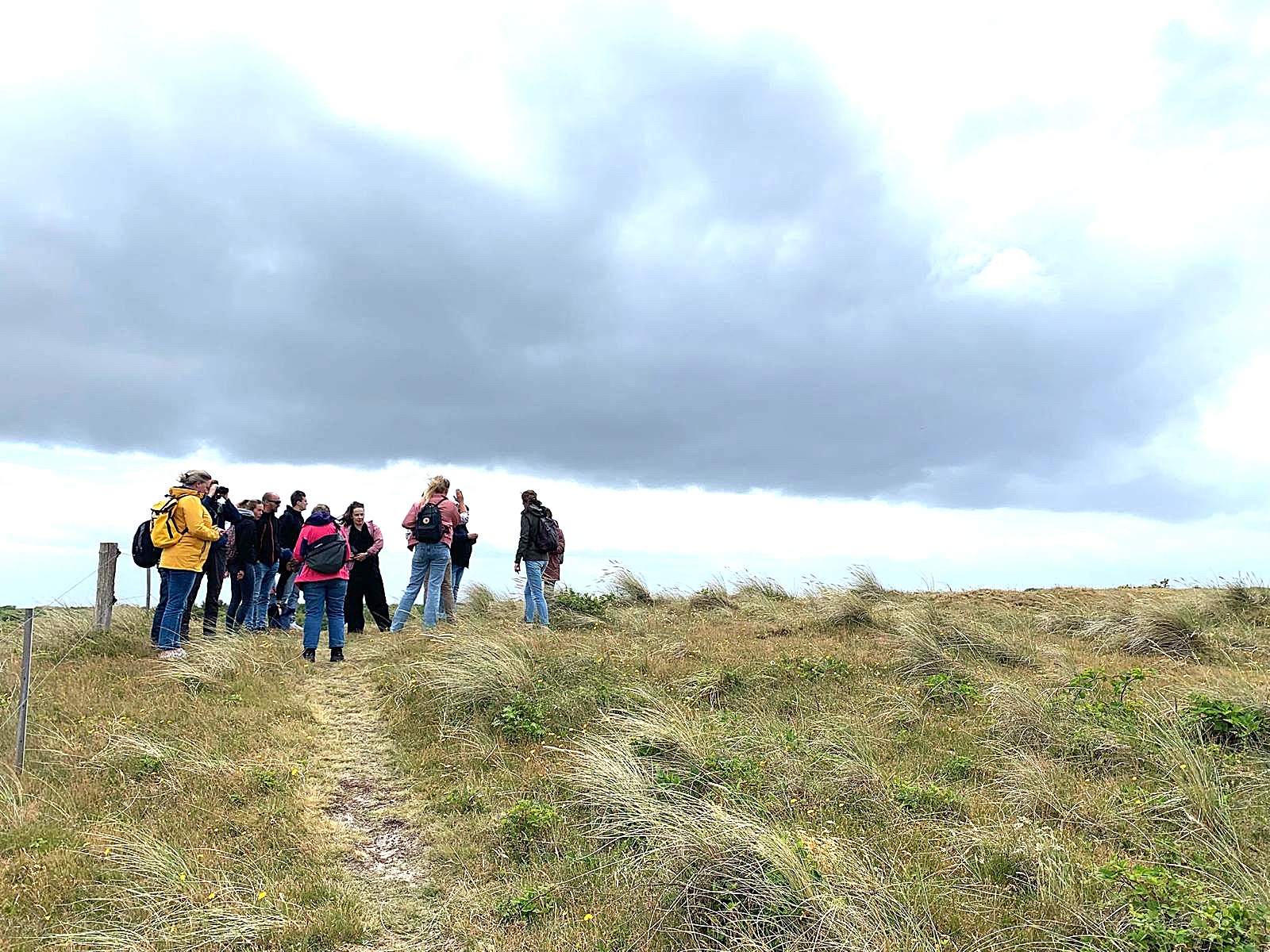Een groepje mensen staan bij elkaar in de duinen van Ameland.
