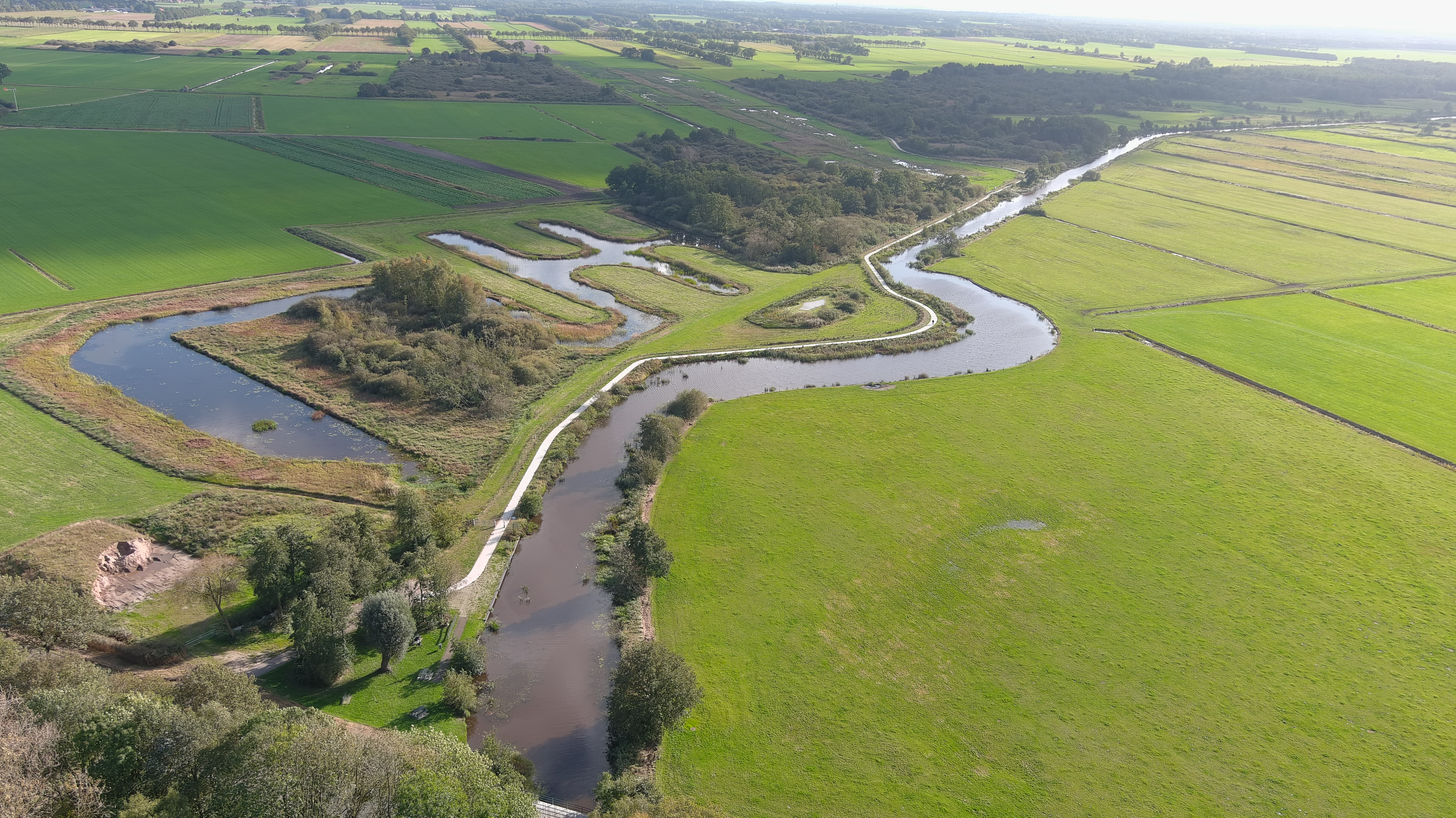 Een rivier meandert door de groene weilanden.