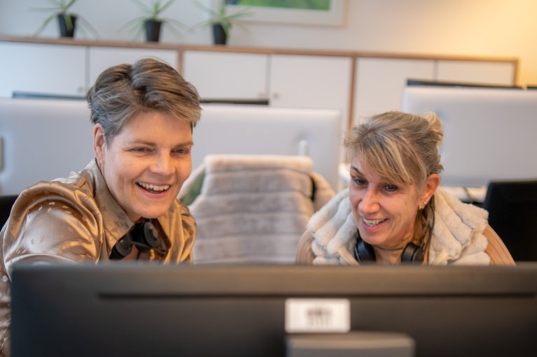 Rixt Bekhuis en Jelly Bosma zitten samen lachend achter de computer.