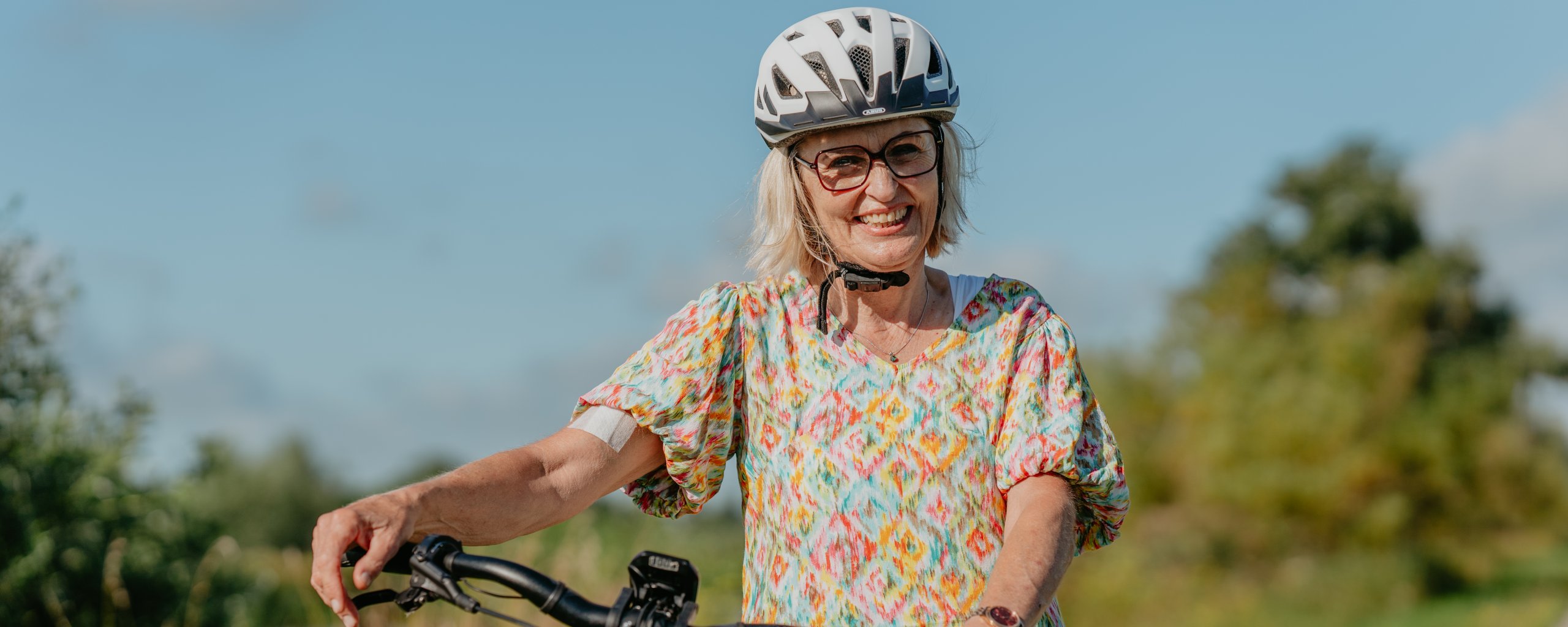 Dame met een fietshelm op en fiets in de hand