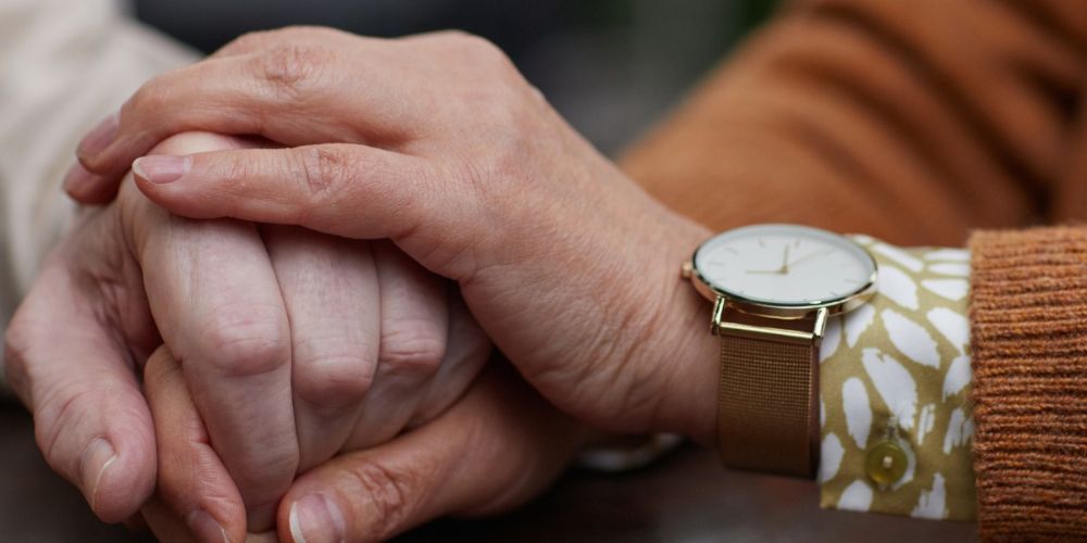 Een intiem en symbolisch moment waarin twee handen elkaar vasthouden. Het is symbolisch voor Zorg in Deurne: warmte, zorg en verbondenheid.