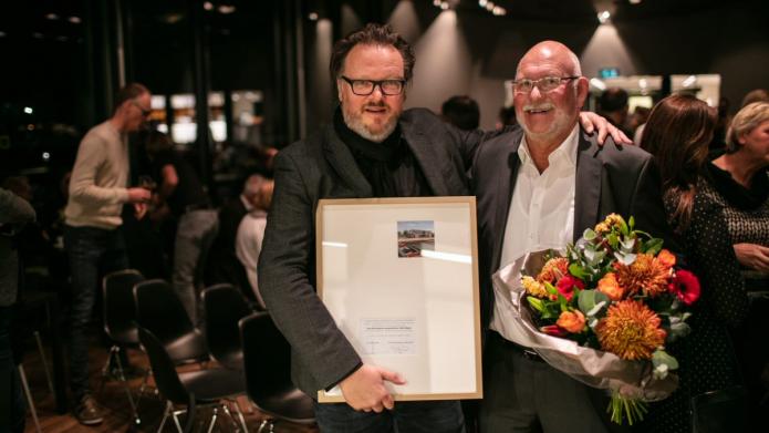 Twee mannen met een bos bloemen en oorkonde in de handen, opdrachtgever - en nemer van het winnende ontwerp van de Vredeman de Vriesprijs voor architectuur.