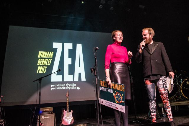 Presentator op het podium samen met gedeputeerde Sietske Poepjes