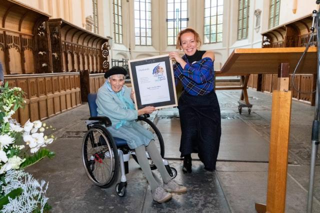 Winnares Aggie van der Meer met gedeputeerde Sietske Poepjes en de gewonnen oorkonde