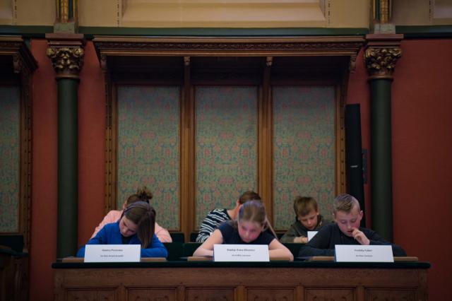 Vooraanzicht van schrijvende kinderen in de Statenzaal