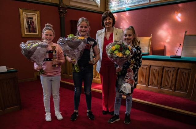 Drie kinderen met boeketten bloemen in hun handen