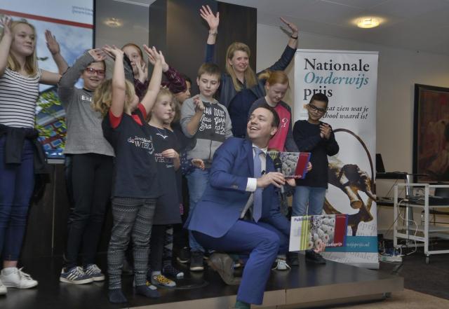 Gedeputeerde Sander de Rouwe poseert met juichende kinderen die op een podium staan