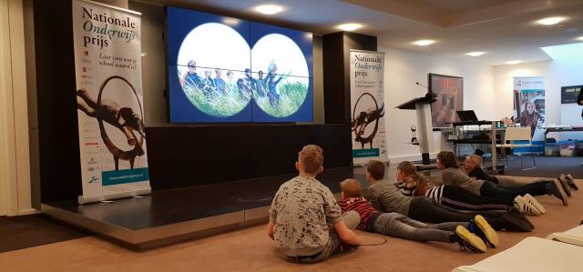 Kinderen kijken naar hun ingestuurde filmpje op groot scherm