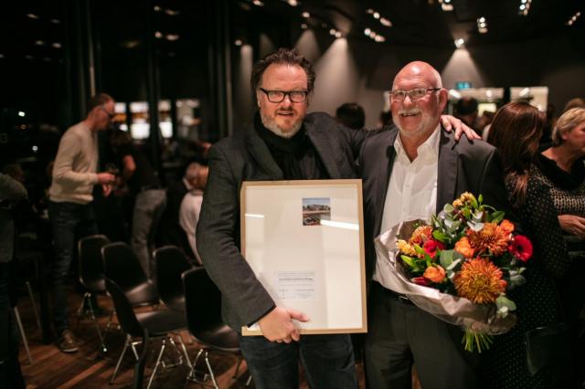Twee mannen met een bos bloemen en oorkonde in de handen, opdrachtgever - en nemer van het winnende ontwerp van de Vredeman de Vriesprijs voor architectuur.
