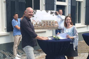 personen rond de ondertekening met het ontwerp op de achtergrond