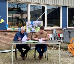 wethouder en aannemer tekenen de overeenkomst aan een tafel voor de oude werf