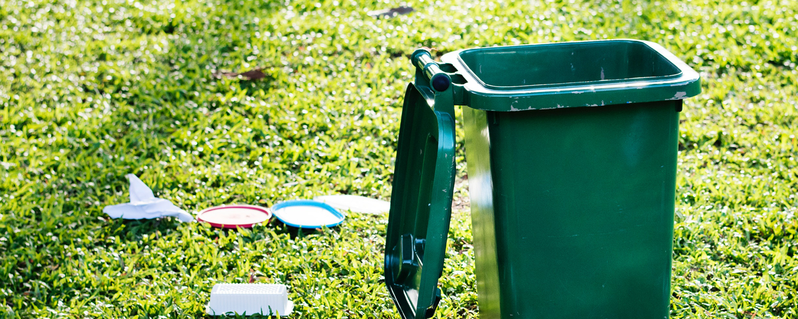 groene container op grasveld met afval naast de container