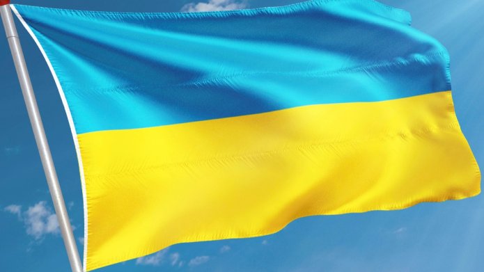De blauw gele vlag van Oekraine wappert tegen de achtergrond van een blauwe lucht.