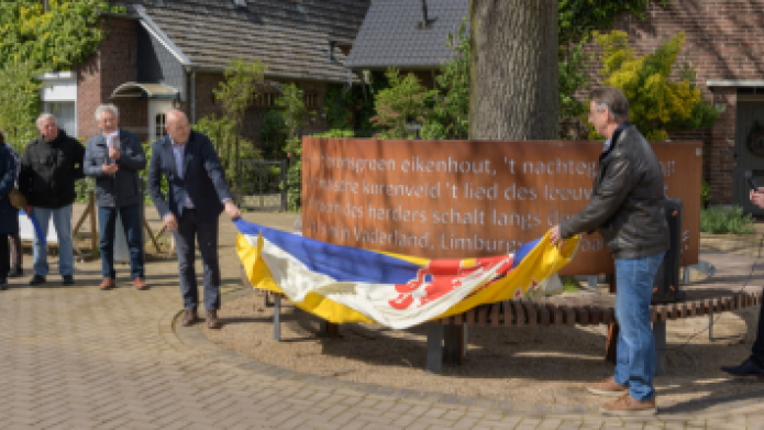 We zien een stalen plaat met de eerste regels van het Limburgs volkslied die wordt onthuld door wethouder Roland Slangen en projectleider Jo Claassen van de gemeente