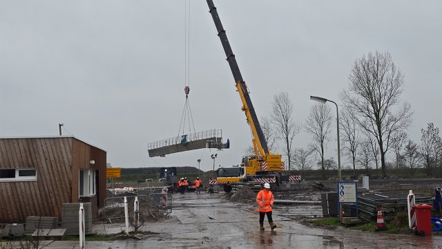 De ruimerbrug wordt met een kraan op z'n plek gehesen.