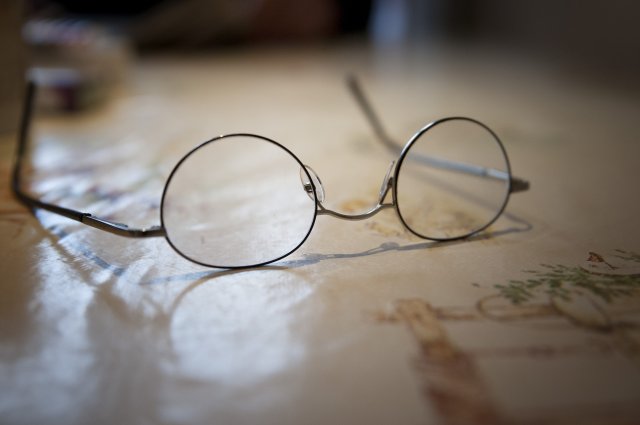 Een bril ligt op tafel.