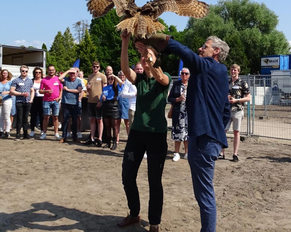 Een oehoe landt op de arm van wethouder Van Ekeren en geeft hem de sleutel van Zelder. 