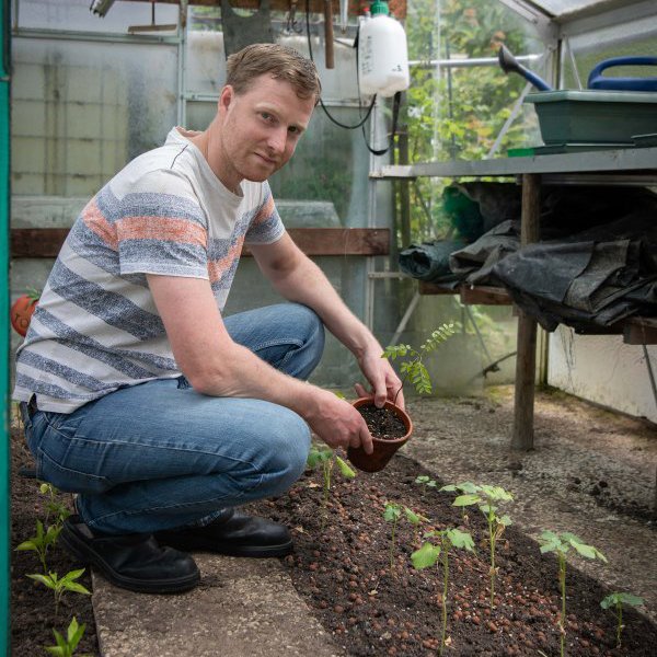 Michael plant plantjes in de kas van de moestuin