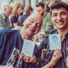 Twee lachende mannen met illustraties.