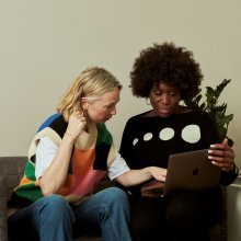 Twee vrouwen op de bank bij een laptop.