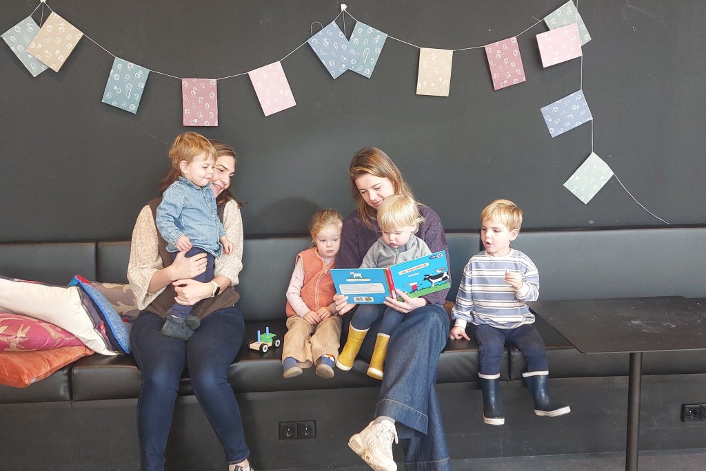 Kinderen lezen met moeders in een prentenboek.