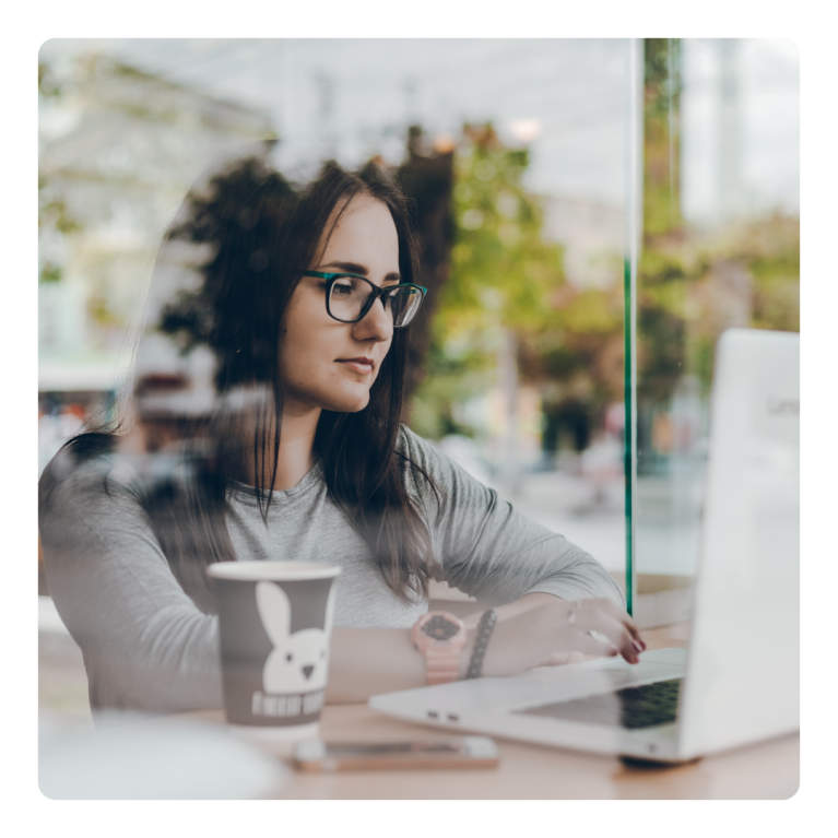 Young adult woman sits behind laptop