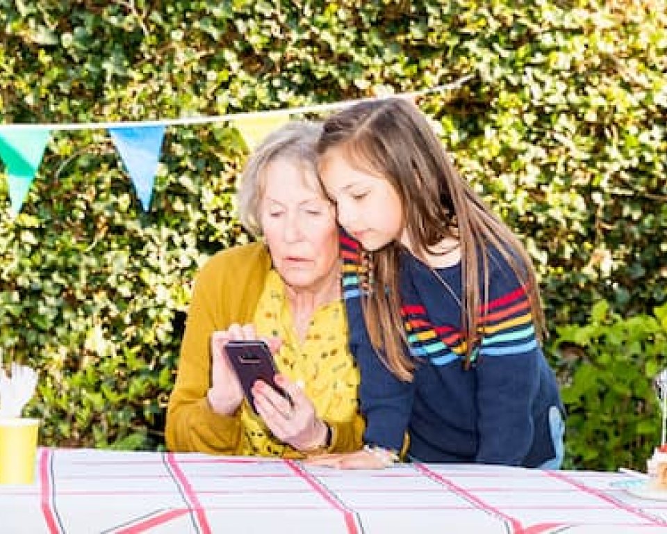 Afbeelding van oma met kleindochter met mobiele telefoon