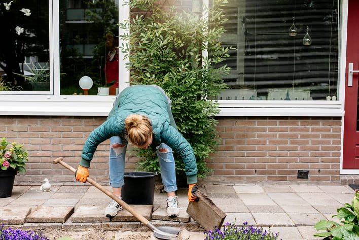 Afbeelding van dame die een tegel van het trottoir verwijdert